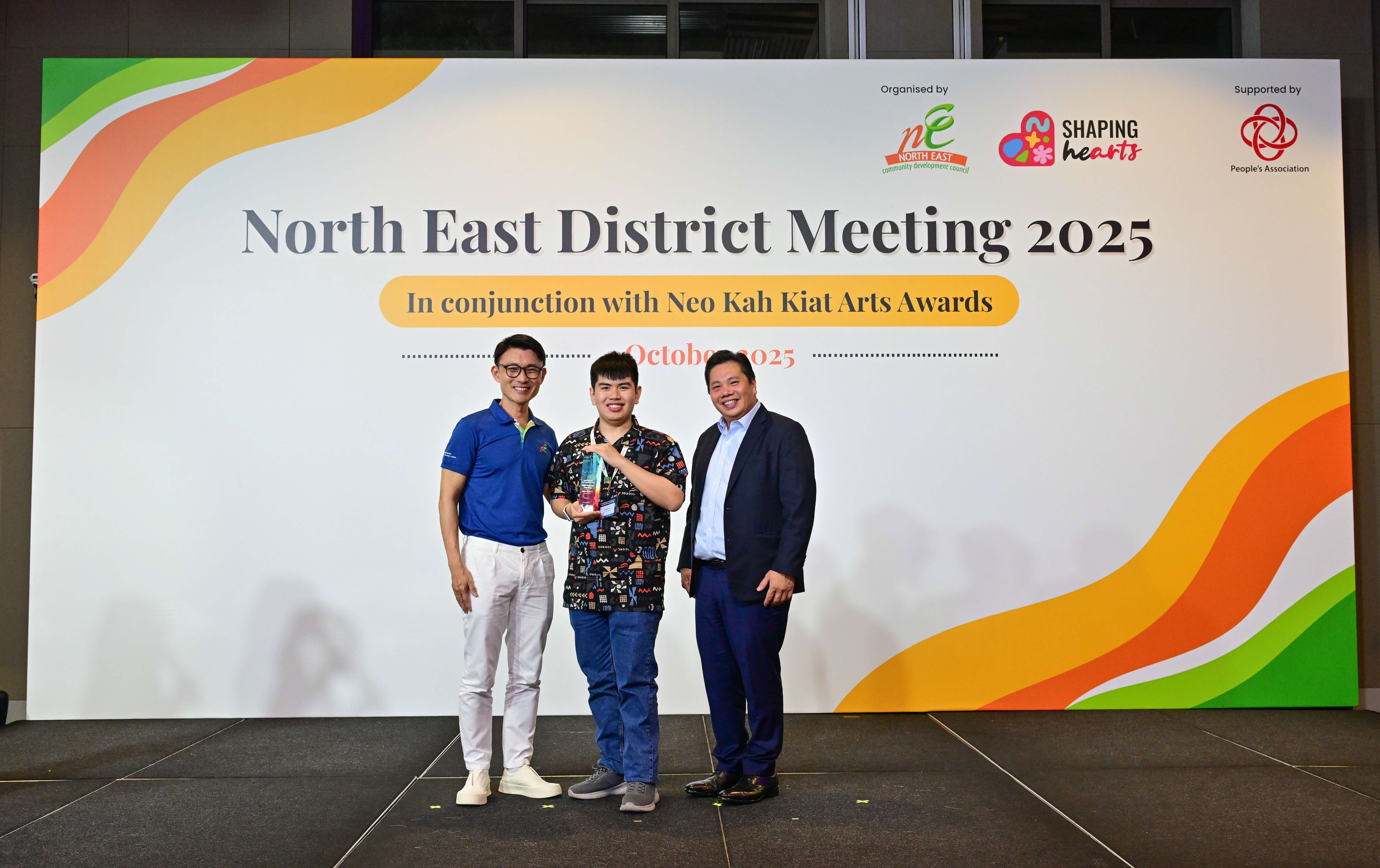 Ezra Chan Yi, recipient of the Neo Kah Kiat Arts Awards Most Popular Painting Award, posing with a trophy alongside Mr Baey Yam Keng and Mr Neo Kah Kiat.